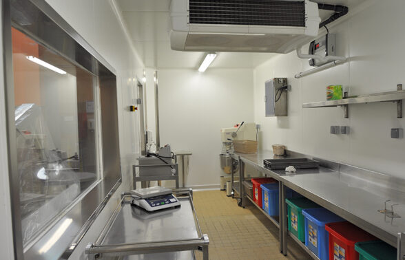 Photo intérieure de la cuisine centrale de Rambouillet. Plans de travail en inox, sol carrelé et équipements de cuisine illustrent cette photo